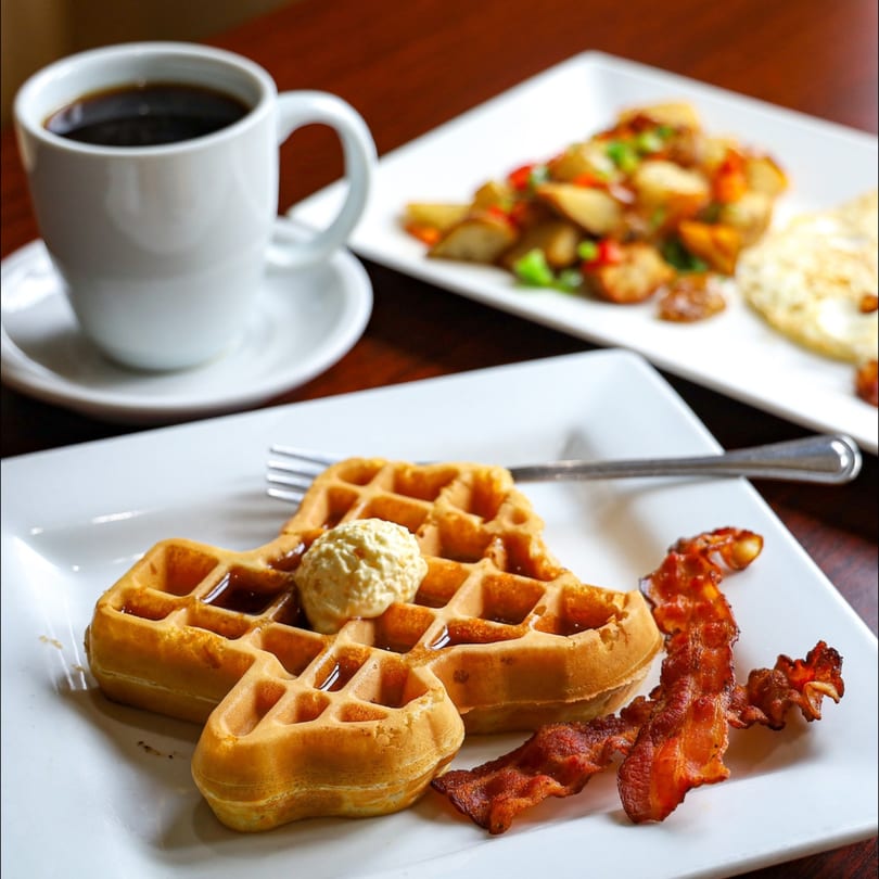Waffles with butter and syrup, bacon, coffee, and breakfast potatoes with eggs at PoPo Family Restaurant.